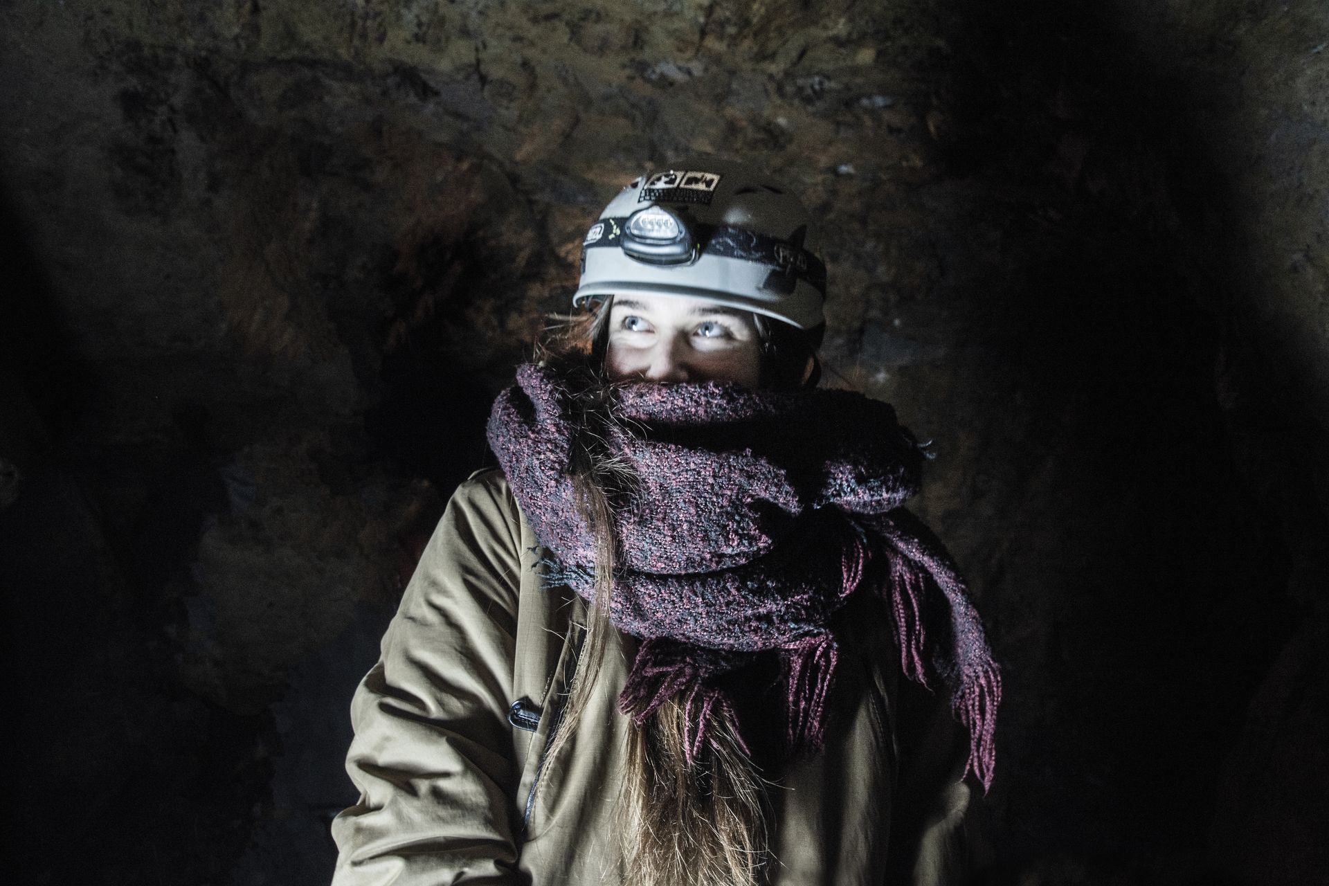 Besucherin mit Helm und Stirnlampe im Stollen